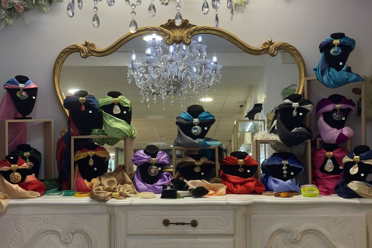 Colliers et foulards présentés devant le miroir doré de la boutique