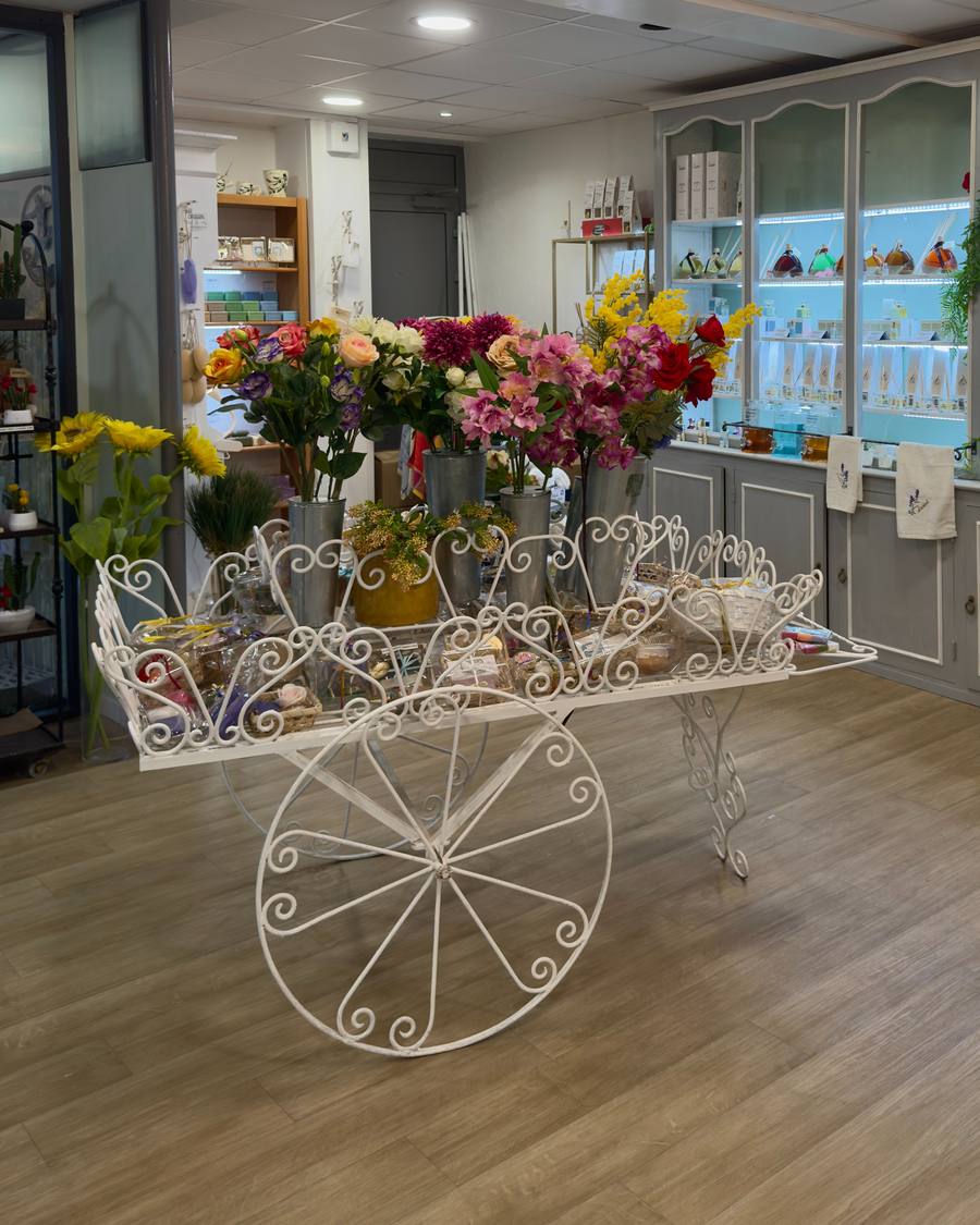 L'intérieur de la boutique Éclats du Sud : charrette fleurie et vitrine de parfums